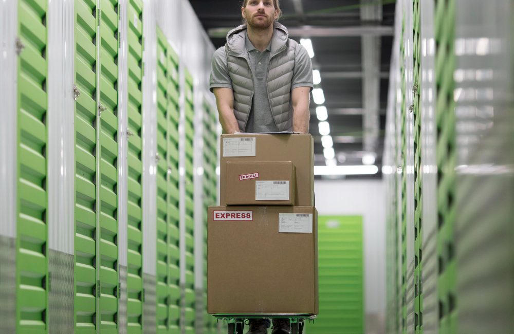man pushing cardboard boxes in self storage area
